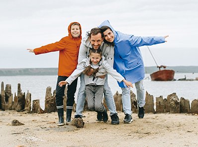 Familie in Regenkleidung am Strand